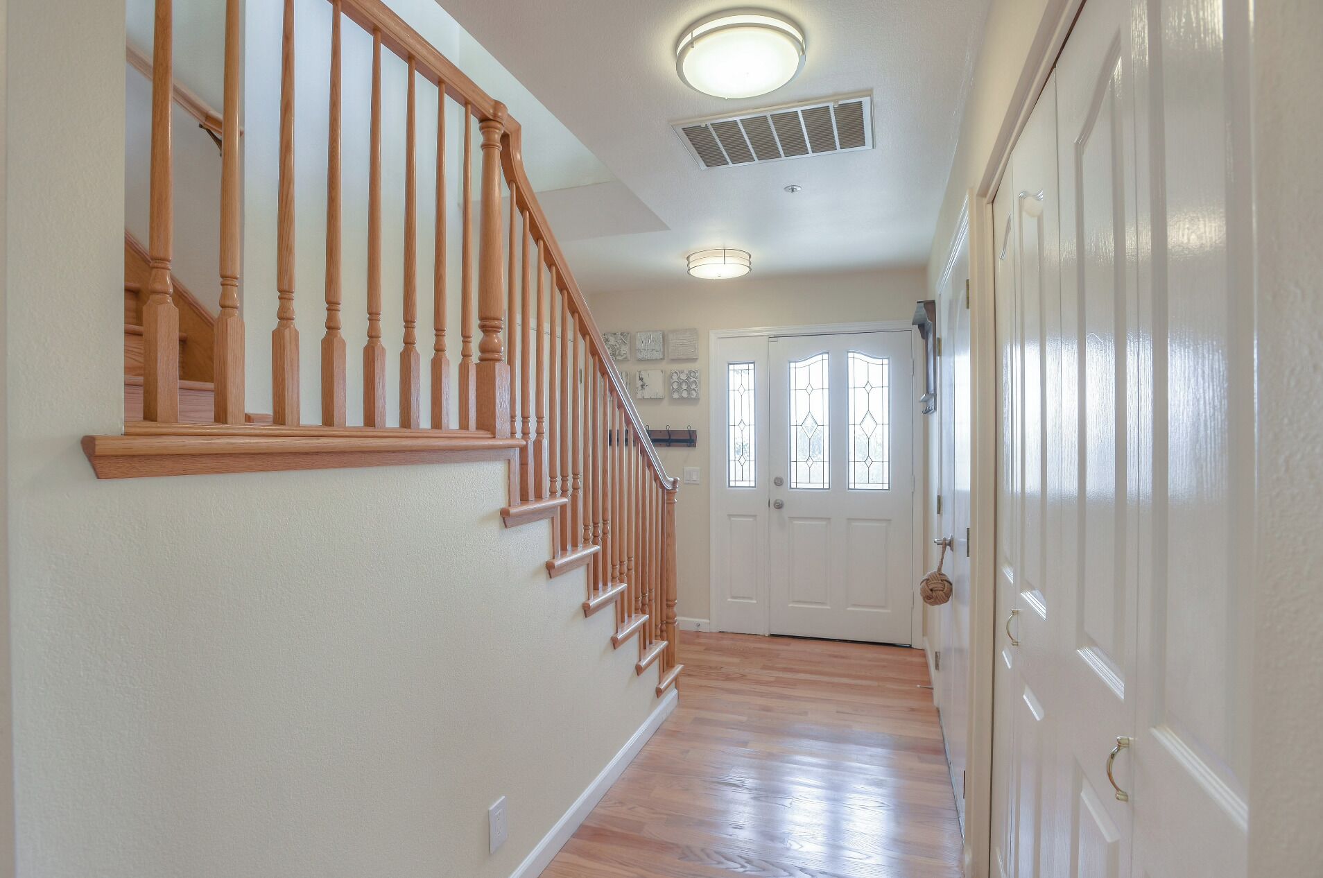 A hallway with wooden stairs, a white door with glass panels, and a ceiling light fixture.
