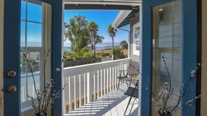 A balcony with a view of the sea, a wooden fence, and a table with chairs. - Gorgeous Half Moon Bay Home (El Granada)
