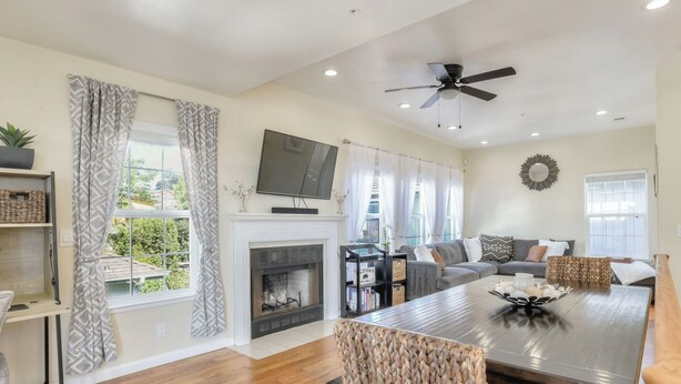 A modern living room with a fireplace, a dining area, and a television mounted on the wall. - Gorgeous Half Moon Bay Home (El Granada)