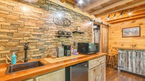 Una cocina con salpicadero de piedra, armarios de madera, un refrigerador de acero inoxidable y una zona de bar con taburetes.