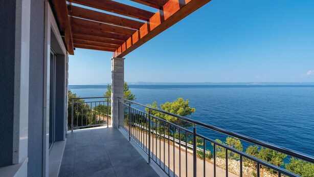 A balcony with a view of the sea and distant mountains.