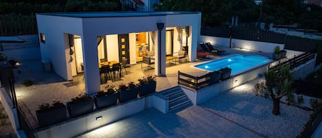 A modern house with a swimming pool, outdoor seating, and a patio area.