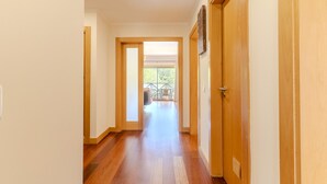 A hallway with wooden flooring and doors leading to a balcony with outdoor furniture.