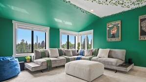 A modern living room with a sectional sofa, a white ottoman, and a blue bean bag. - *Spectacularly Spacious*  6-Person Sauna |Rocket-ship|Game-Room|Hammock (Calgary)
