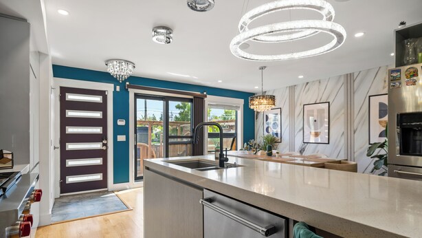 A modern kitchen with a large island, stainless steel appliances, and a chandelier. - *Spectacularly Spacious*  6-Person Sauna |Rocket-ship|Game-Room|Hammock (Calgary)