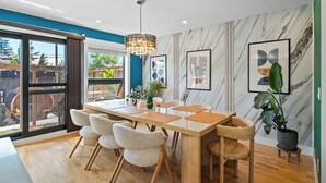 A modern dining area with a wooden table, chairs, and a chandelier. - *Spectacularly Spacious*  6-Person Sauna |Rocket-ship|Game-Room|Hammock (Calgary)