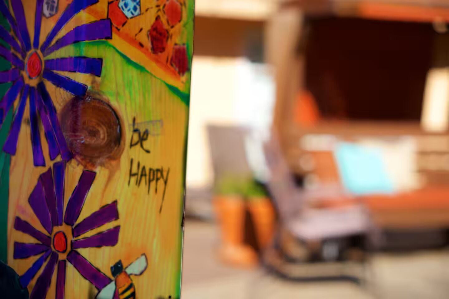 Pared colorida con una ilustración de abeja y la frase 'be happy' escrita.