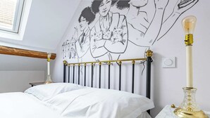 A bedroom with a bed, a radiator, a wall-mounted light fixture, and a decorative table lamp. - Logis Colette (flavigny sur Ozerain)