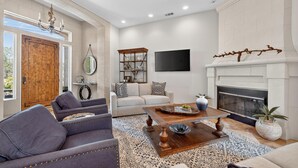 A living room with a fireplace, sofa, coffee table, and a television.