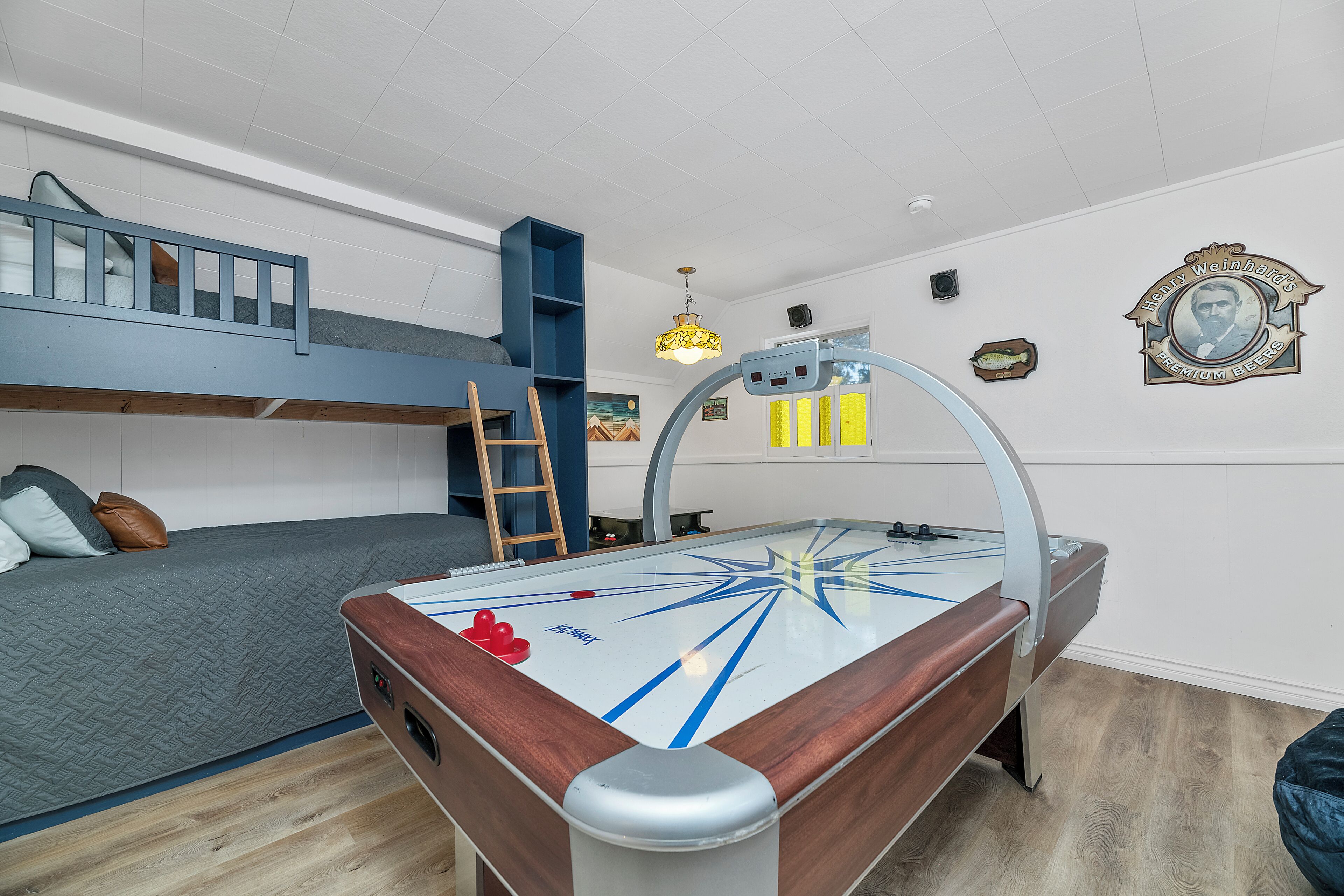 A room with a pool table, bunk beds, a ladder, and a ceiling fan.