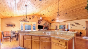 A spacious kitchen with wooden cabinets, a large island, and a stone floor.