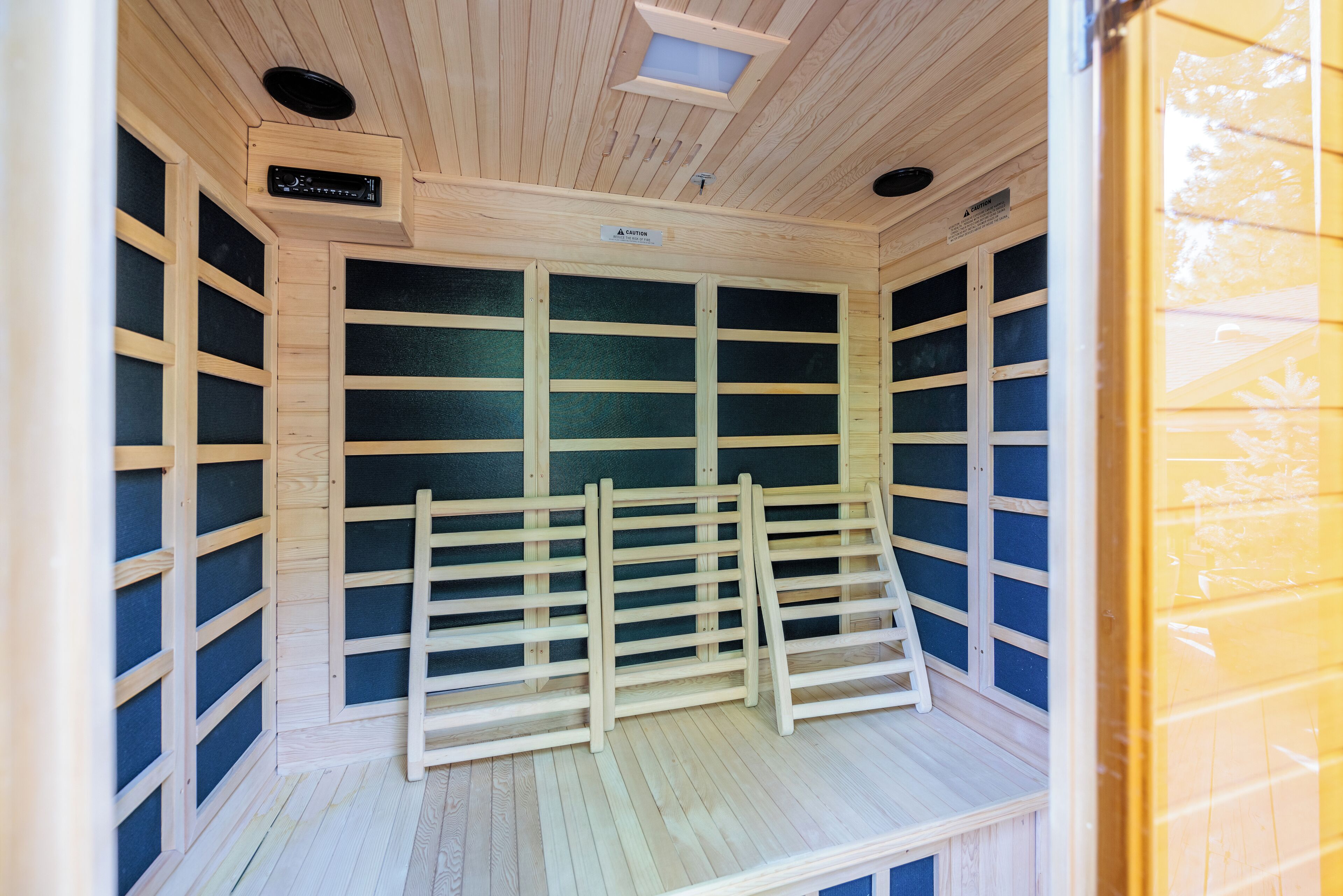 A sauna room with wooden walls, a bench, and a ceiling vent.