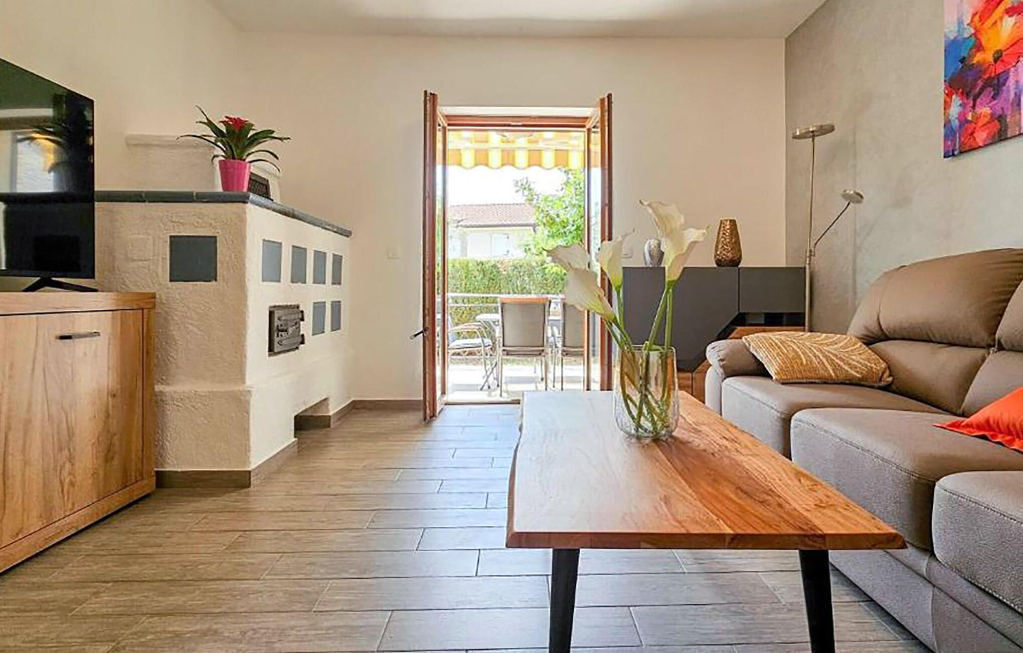 A modern living room with a wooden coffee table, a grey sofa, and a TV on a cabinet.