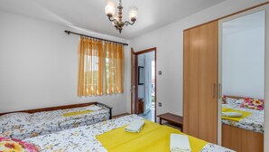 Ein Hotelzimmer mit zwei Betten, einem Holzschrank, einem Spiegel und einer Deckenleuchte.