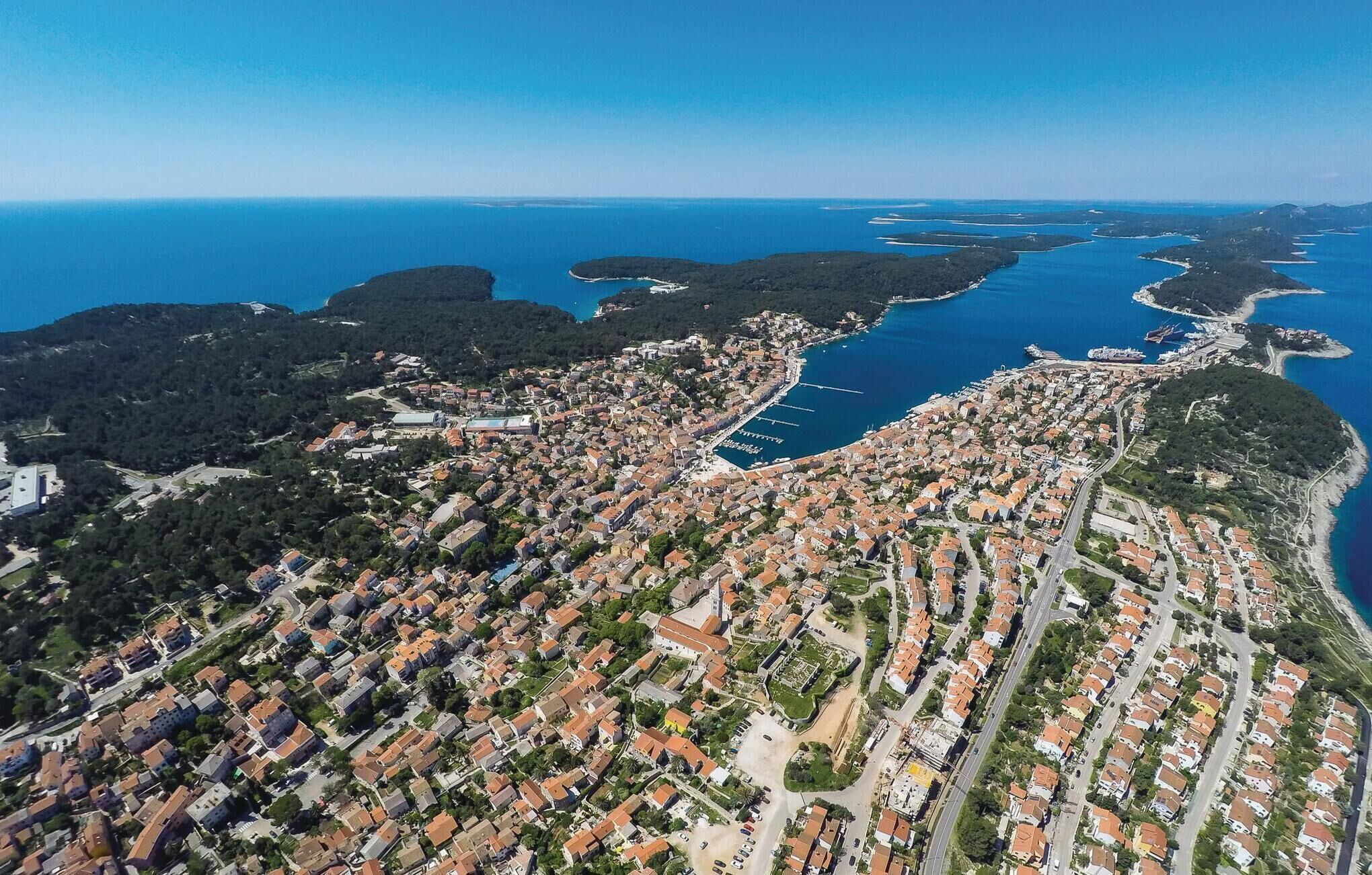 An aerial view of a coastal town with a dense residential area, a marina, and a large body of water.