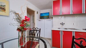 Una cocina moderna con armarios rojos, una mesa de comedor de cristal y un jarrón con flores.