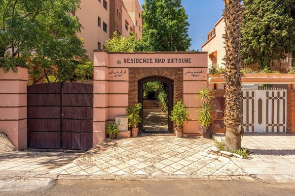 A gated entrance with a sign reading 'Residence Rd Zaitoune' and a tiled pathway leading to the gate.