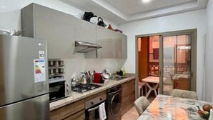 A modern kitchen with stainless steel appliances, wooden cabinets, and a dining area with a marble table. - Secure residence with pool & fiber (Marrakesh)