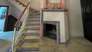 A staircase with patterned steps leading to a landing with a decorative fireplace and wall sconces. - Duplex in City Center - Patio & Parking (Marrakesh)