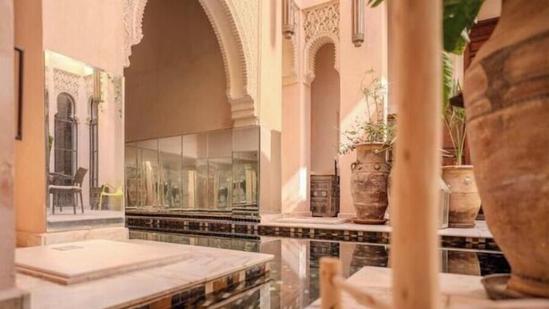 A luxurious interior with a marble floor, a glass partition, and a seating area with a chair and a table. - Riad MAYAN : Heated Pool & GYM (Marrakesh)