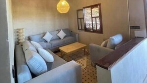 A cozy living room with a thatched ceiling, a sofa set, a coffee table, and a hanging light fixture. - Skoura Ranch - Palmeraie (Skoura)