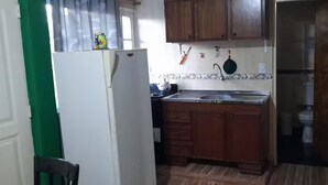 Una cocina compacta con armarios de madera, un refrigerador blanco, un lavamanos y salpicadero de azulejos.