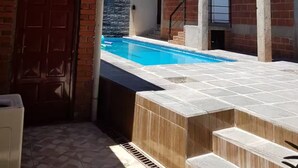 Un edificio de dos pisos con piscina, techo de madera y fachada de ladrillo.
