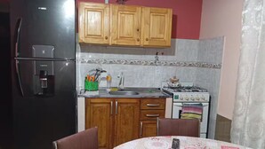 Cozinha com armários de madeira, geladeira, pia e fogão.