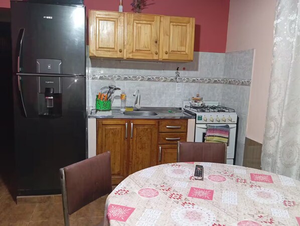 A kitchen with wooden cabinets, a refrigerator, a sink, and a stove.