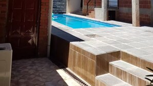 Um edifício com vários andares, piscina, escadas externas e uma porta.