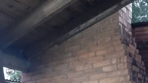 Forno de tijolos ao ar livre com chão de pedra, rodeado por lenha e um cesto verde.