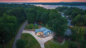 An aerial view of a house with a large driveway, surrounded by dense trees and a lake. - Cove's End by Avantstay Dock, Game Room, Fire Pit & Forest Views (Mooresville)