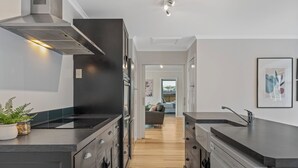 A modern kitchen with dark cabinetry, stainless steel appliances, and a central island. - Family Fun Haven (Taupo)