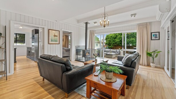 A spacious living room with a fireplace, a dining area, and a kitchen. - Family Fun Haven (Taupo)