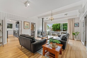 A spacious living room with a fireplace, a dining area, and a kitchen. - Family Fun Haven (Taupo)