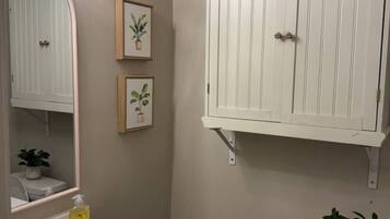 Un bany amb un lavabo blanc, mirall i armari. Hi ha dos quadres a la paret.