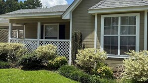 A two-story house with a covered porch, a fenced yard, and a well-maintained lawn. - Charming 2-bedroom house in Flowood, Pet Friendly w/Fenced Backyard and Sunroom (Brandon)