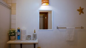 Een badkamer met een spiegel, een handdoekhouder, een zeester decoratie en een plank met toiletartikelen.