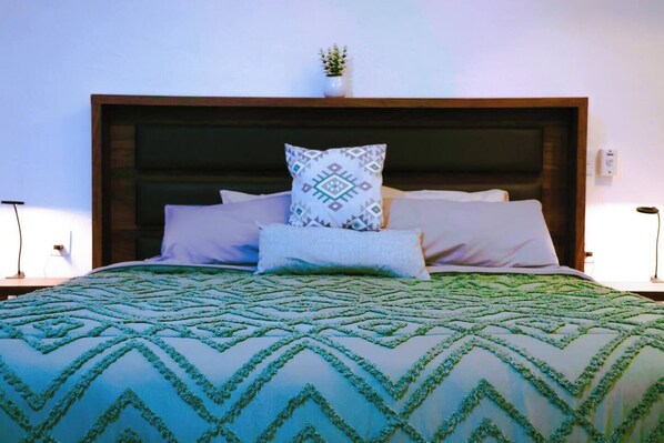 A neatly made bed with patterned bedding, a wooden headboard, and two bedside lamps.