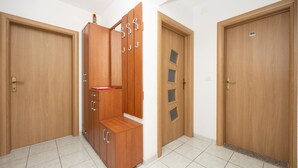 Una habitación con dos puertas de madera, un armario con varios compartimentos y un suelo de baldosas.