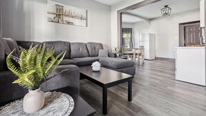 A modern living room with a grey sectional sofa, a coffee table, and a potted plant.