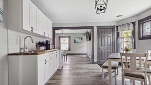 A modern kitchen with white cabinets, a wooden countertop, and a dining area with a table and chairs.