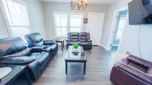 A modern living room with leather sofas, a coffee table, and a chandelier. - Family-Friendly 3Br-Free Parking & Wifi (Niagara Falls)