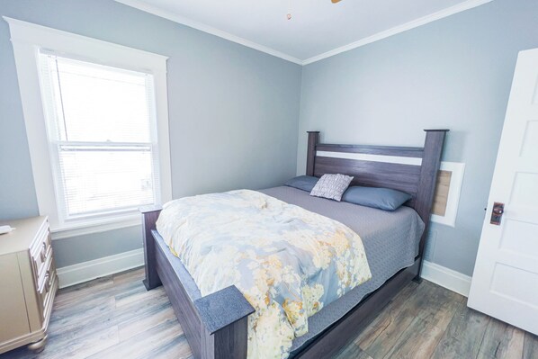 Un dormitorio con cama, cómoda, ventana y puerta.
