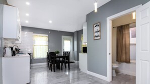 A modern kitchen with white cabinets, a dining area with a table and chairs, and a grey tiled floor. - Double House Rental – 11Br Perfect For Big Groups (Niagara Falls)