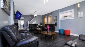 A modern living room with leather sofas, a coffee table, and a staircase leading to another level. - Double House Rental – 11Br Perfect For Big Groups (Niagara Falls)