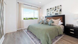 Ein Schlafzimmer mit einem großen Bett, Blick ins Freie durch ein Fenster, einem Kopfteil und einem Nachttisch.