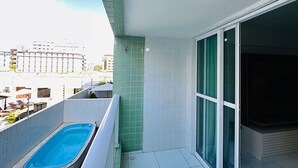Un balcón con piscina, una pared verde de azulejos y vistas a la ciudad.