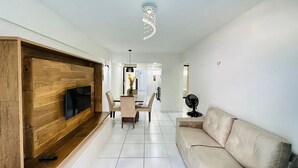 Una sala moderna con televisor empotrado, comedor y sofá.
