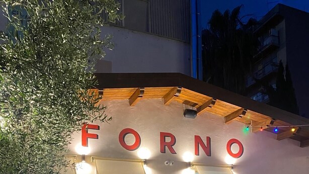 A cozy outdoor seating area with a table and chairs, a chalkboard menu, and a sign that reads "FORNO". - Cris al Pigneto is a B&B Comfortable, bright and well connected to the center. (Roma)
